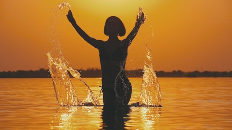 Silhouette of a woman in the pool against the sunset.