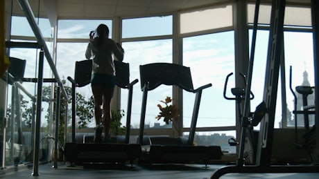 Silhouette of a woman running in the treadmill.