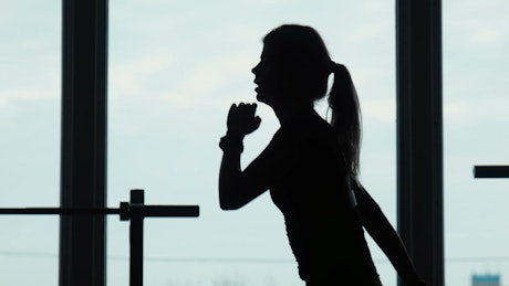 Silhouette of a young woman doing squats