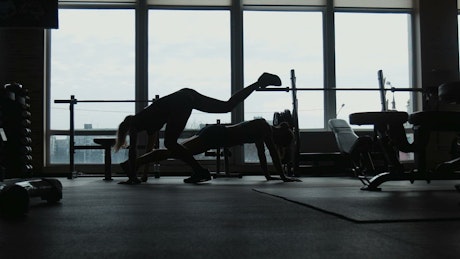 Silhouette of girls doing push-ups together.