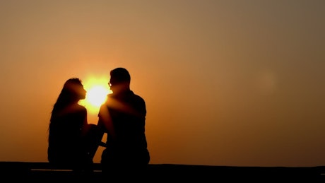 Silhouette of lovers at sunset, static shot.