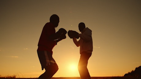 Silhouette of two people working out with boxing training.