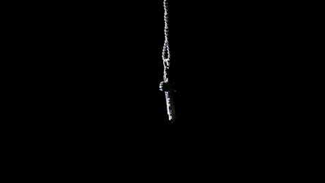 Silver crucifix necklace on black background.
