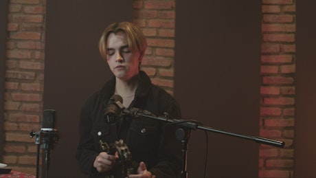 Singer recording vocals in a studio with a tambourine