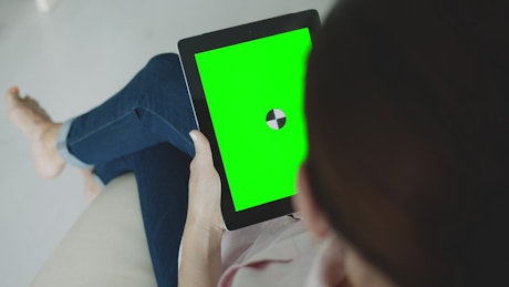 Sitting woman holding greenscreen tablet with chroma key