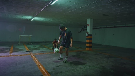 Skilled freestyler juggling the ball in a parking lot.