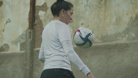 Skillful female soccer player doing ball juggling