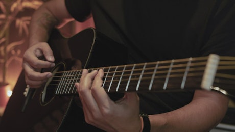 Skillful guitarist playing a black guitar.