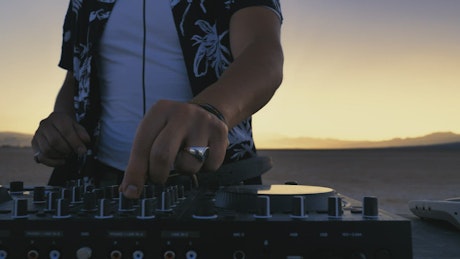 Skillful hands of a DJ mixing music outdoors.