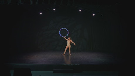 Skillful woman doing tricks with a hula hoop.
