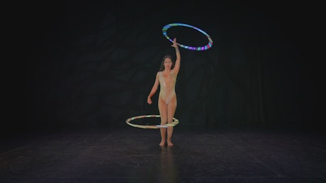 Skillful woman spinning two hula hoops