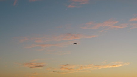 日落时的天空视图，远处有一架飞机