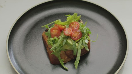 Slice of bread with salad on a plate.