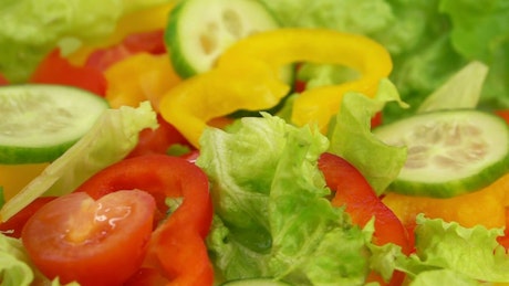 Slices of vegetables falling over salad.