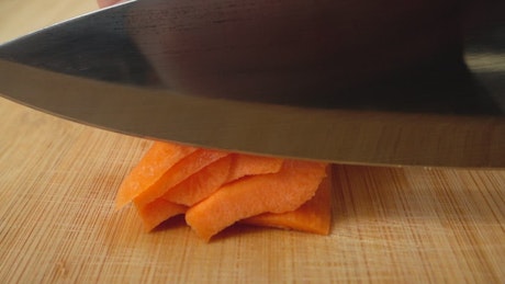 Slicing carrot on a board.