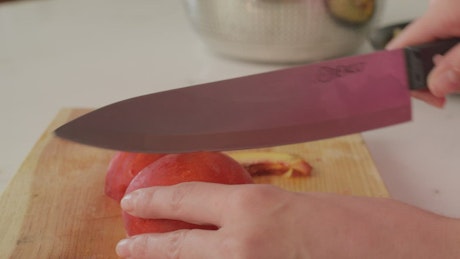 Slicing peach on a wooden board.