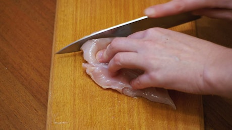 Slicing raw chicken meat.