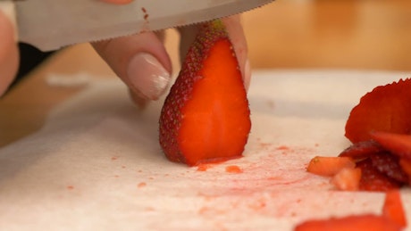 Slicing strawberries to decorate a cake.