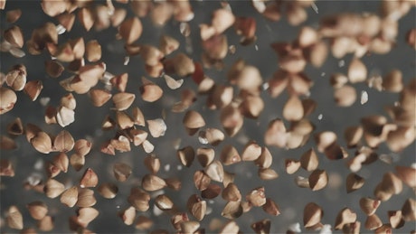 Slow motion pieces of almonds falling into the air.