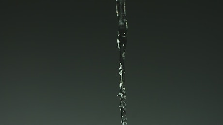 Slow motion water stream pouring into a glass.