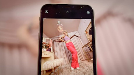 Smartphone recording a young woman modeling for social media post.