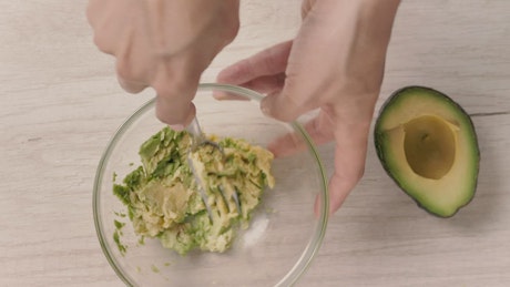 Smashing avocado in a bowl.