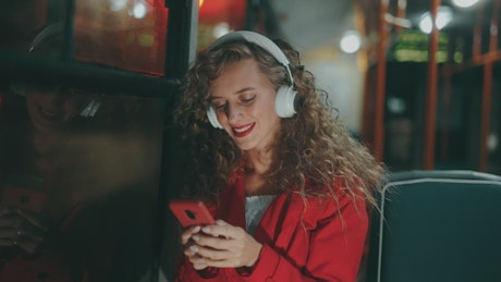 Smiling curly girl listening music on a bus.