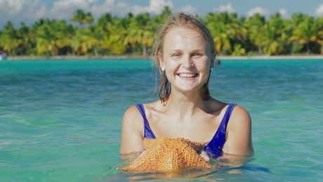 Smiling woman holding a starfish