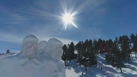 Snow statues on a snowy mountain range with skiers.