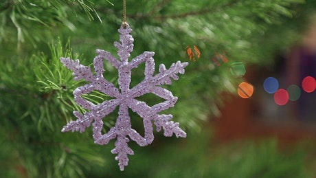 Snowflake Christmas decoration dangling off a Christmas Tree.