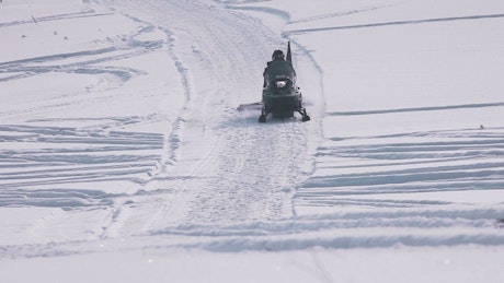 Snowmobile being driven through fresh snow.