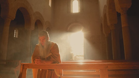 Soldier-warrior prays on his knees in the church.
