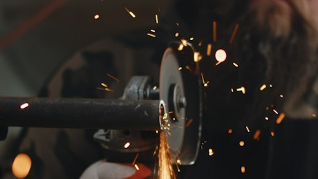 Sparks flying off of an angle grinder cutting a piece of metal.