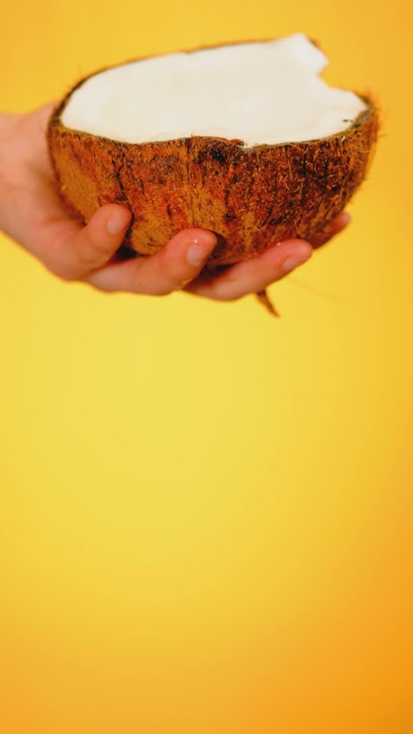 Spilling water from a coconut on a yellow background.