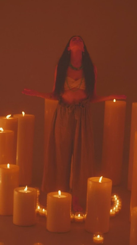 Spiritual girl meditating among many burning candles.