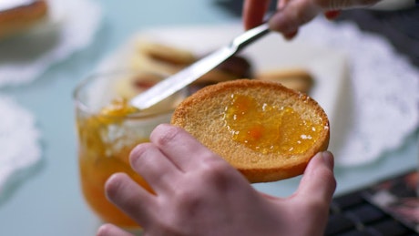 Spreading marmalade on toasted crumpets.