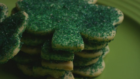 Stack of green cookies in the shape of clovers.