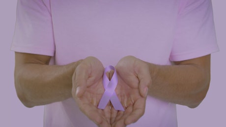 Stomach cancer ribbon in the hands of a man.