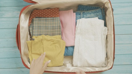 Stop motion of packing a suitcase for summer vacation.