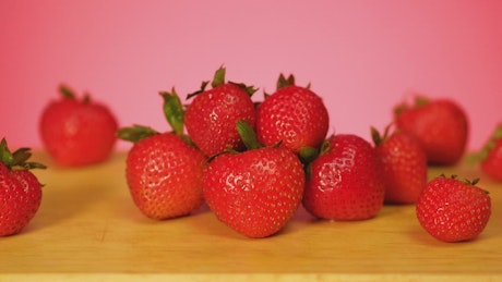 草莓上覆盖着粉红色背景的巧克力