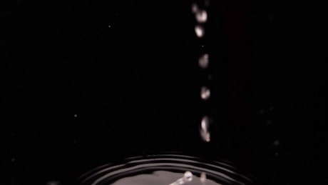 Strawberries falling into a black water.