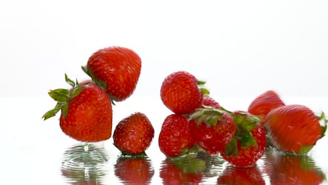 Strawberries falling on a surface on a white background