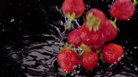 Strawberries falling to black water