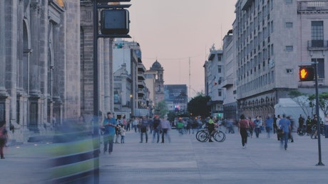 Street with people walking at dusk.