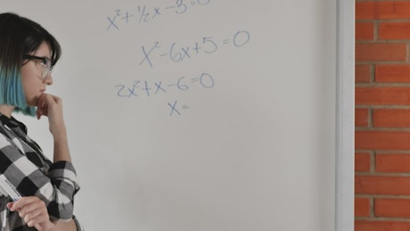 Student girl trying to solve equations on the whiteboard