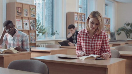 Student with book and tablet in the library
