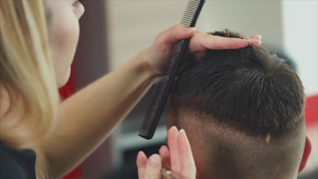 Stylist cutting a boy's hair.