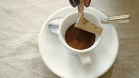 Sugar being poured into a cup of espresso.