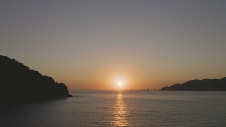 Sun setting on the horizon line at sea.