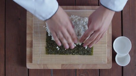 Sushi rice being flattened while making sushi.